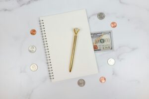 hand writing debt list in notebook at desk