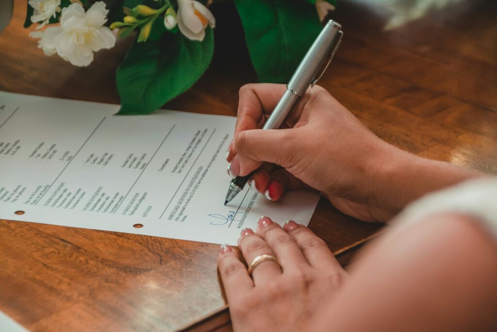 hand signing loan document with pen on paper
