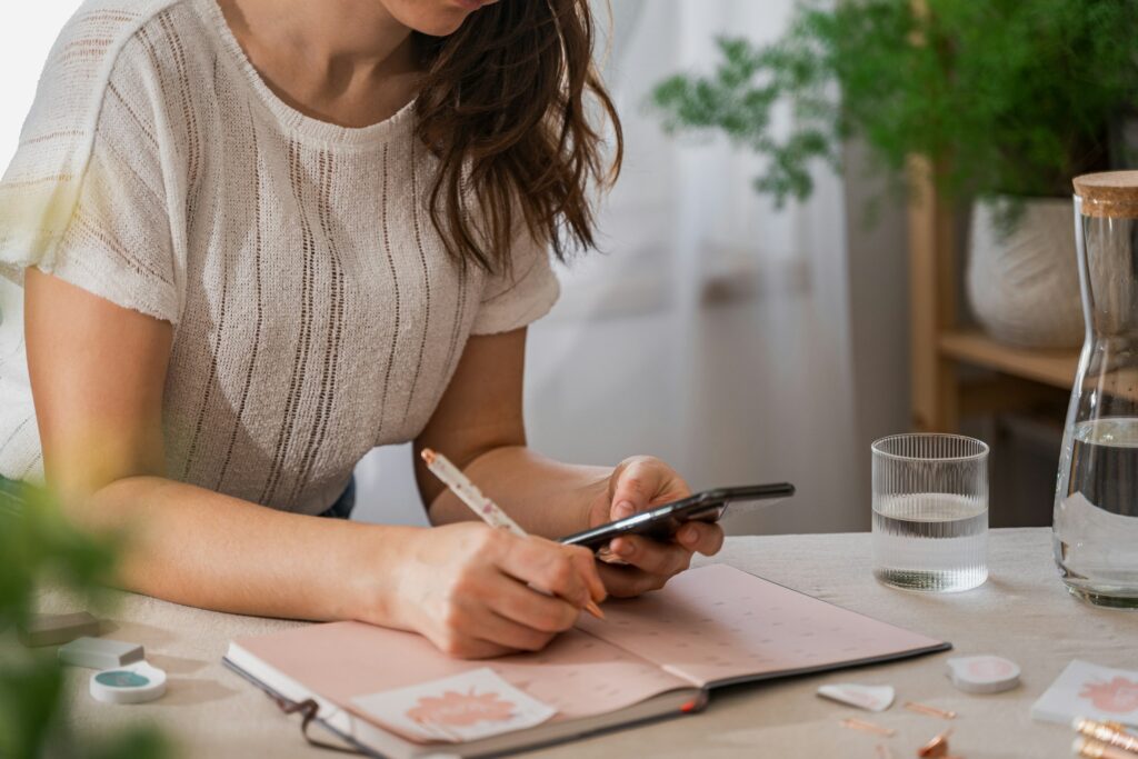 woman writing savings plan in notebook at table